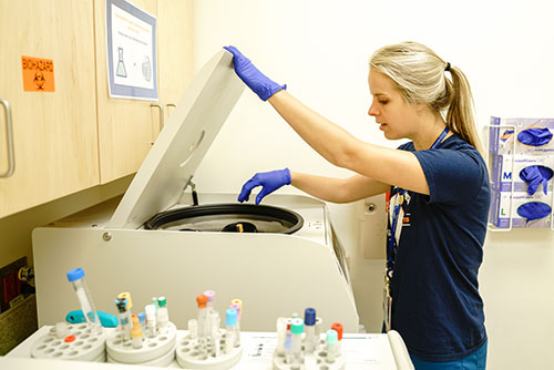 Woman looking in a centrifuge Woman looking in a centrifuge