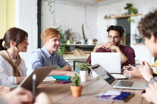 Group of people sitting at a table with laptops working together.