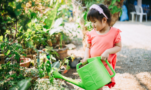 Image of girl watering plants outside.