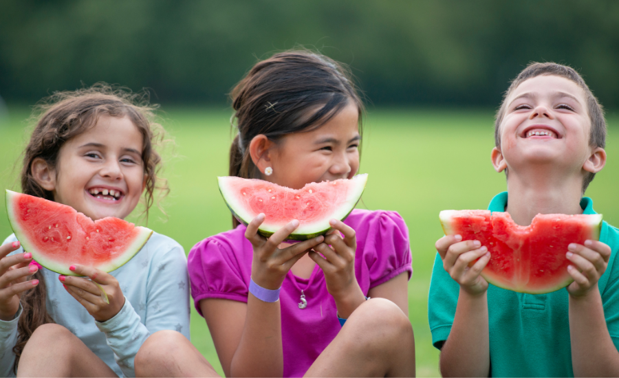 Three children smiling and eating watermelon